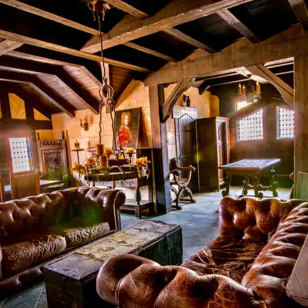 a room with old comfy leather couches and exposed wood beams